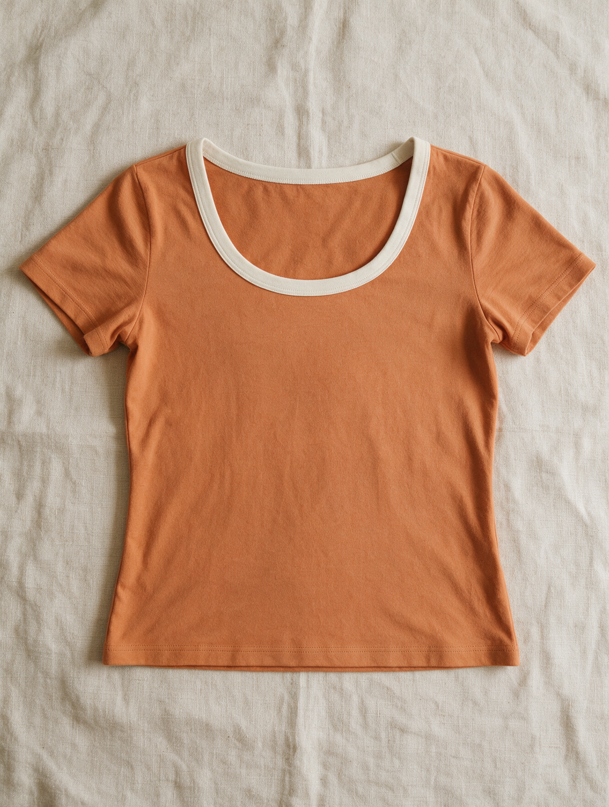 The Fitted Tee in Sunrise — laid flat on linen